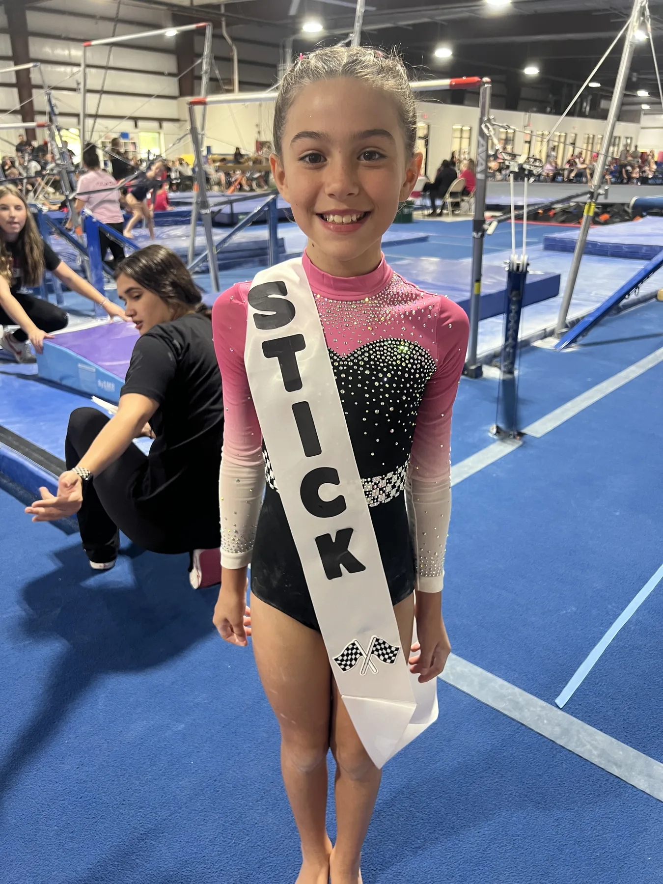 Winner Circle Athletics gymnast holding a STICK sign at a meet