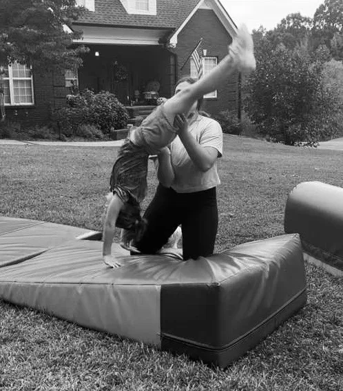 Winner Circle Athletics coach spotting a young gymnast through a skill on the mat